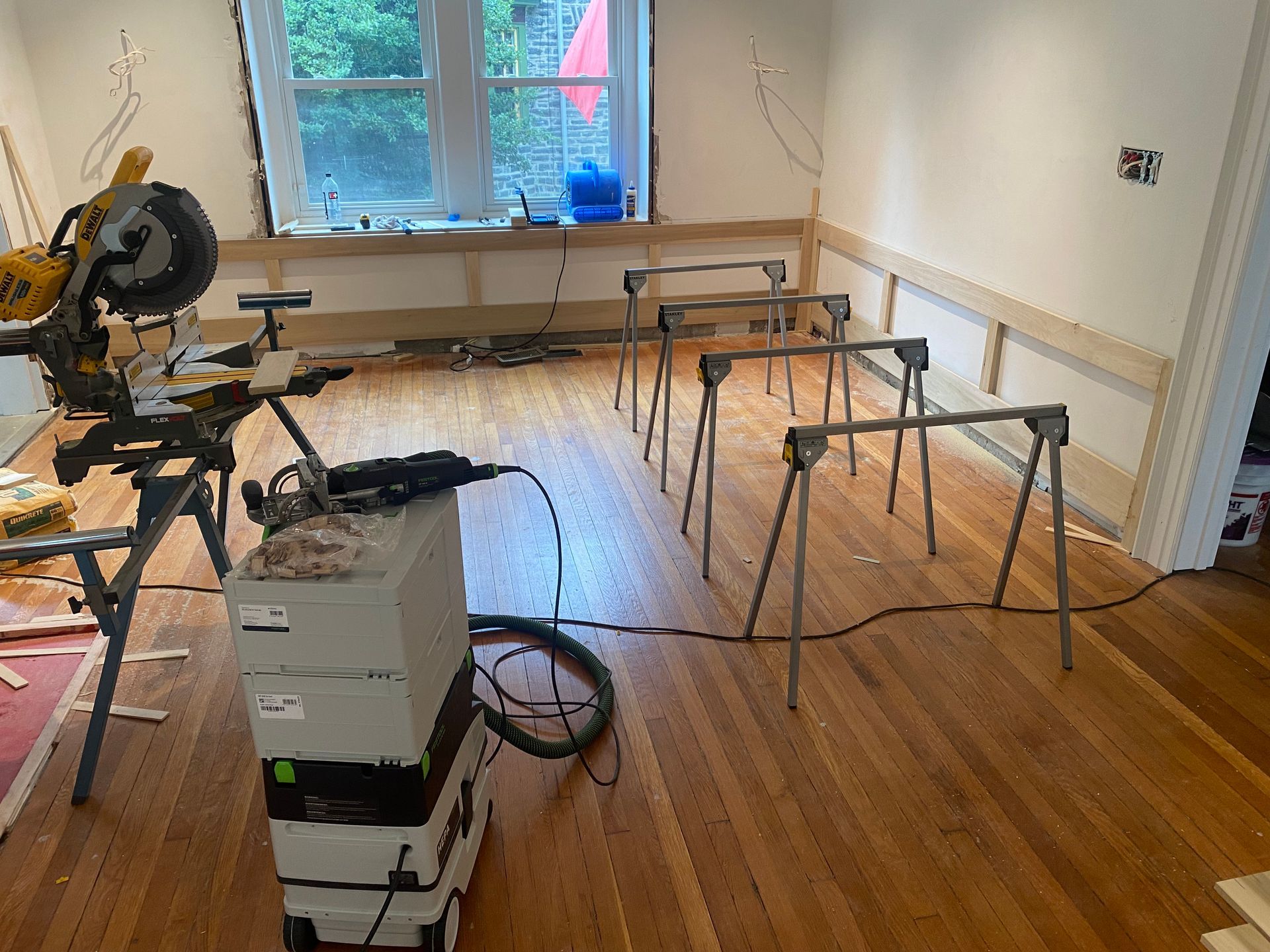 A room with wooden floors and a sliding saw on the floor.