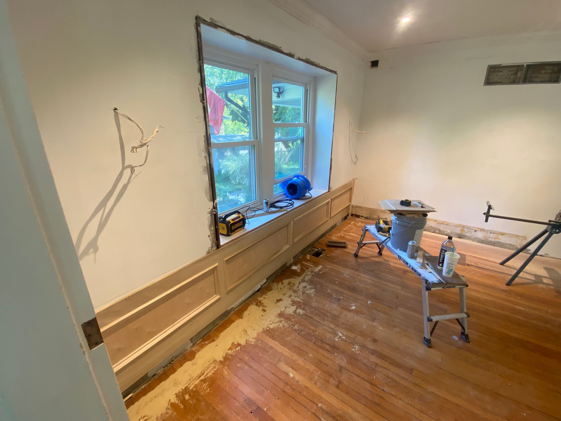 A room with a wooden floor and a window being remodeled.