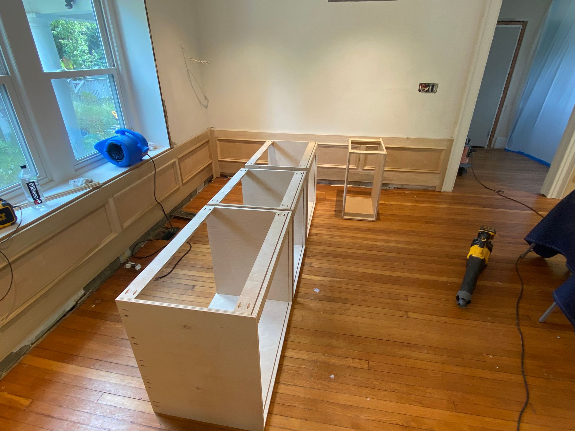 A room with wooden floors and white cabinets being built