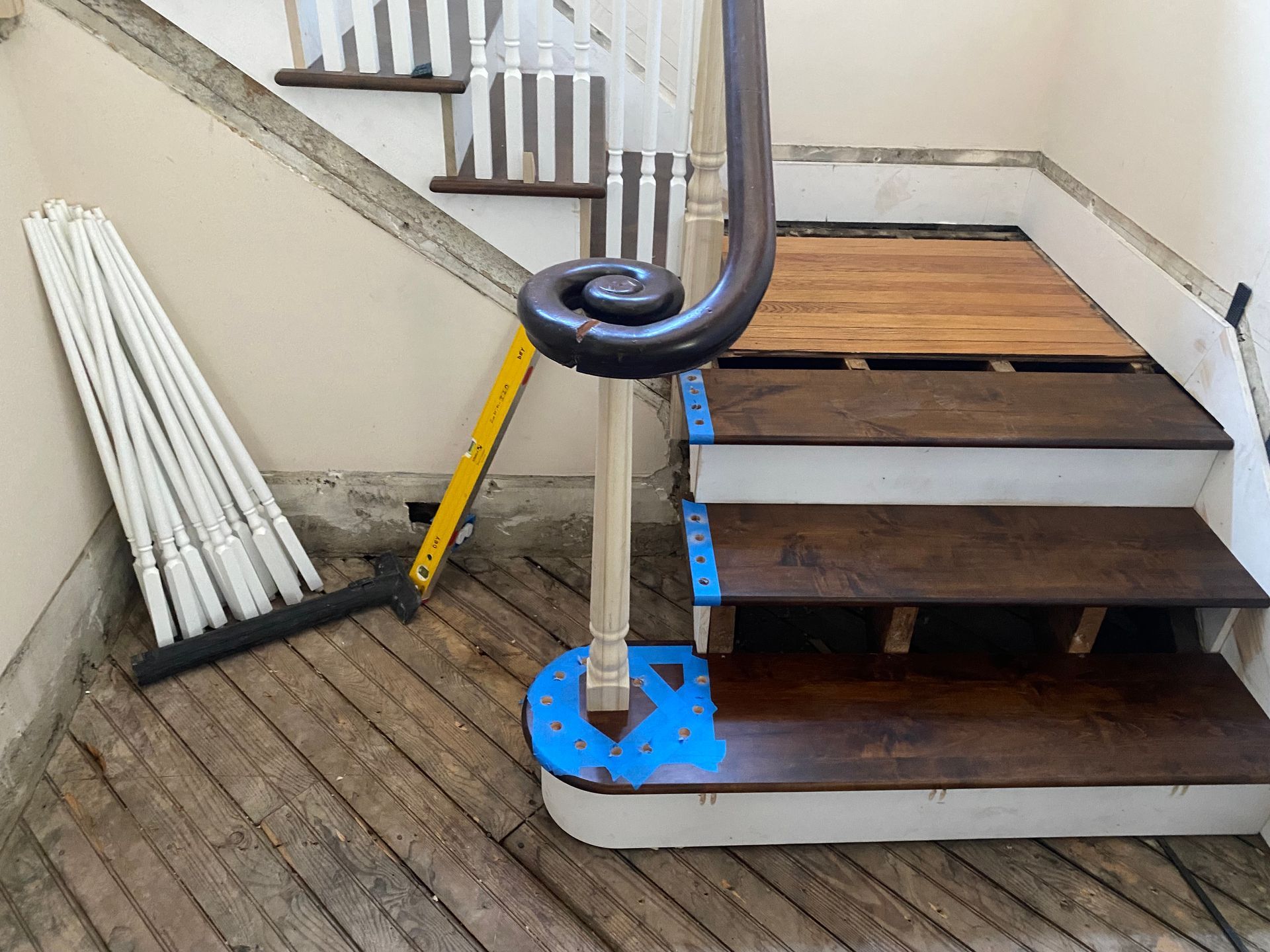 A wooden staircase with a broom and a ruler on the floor