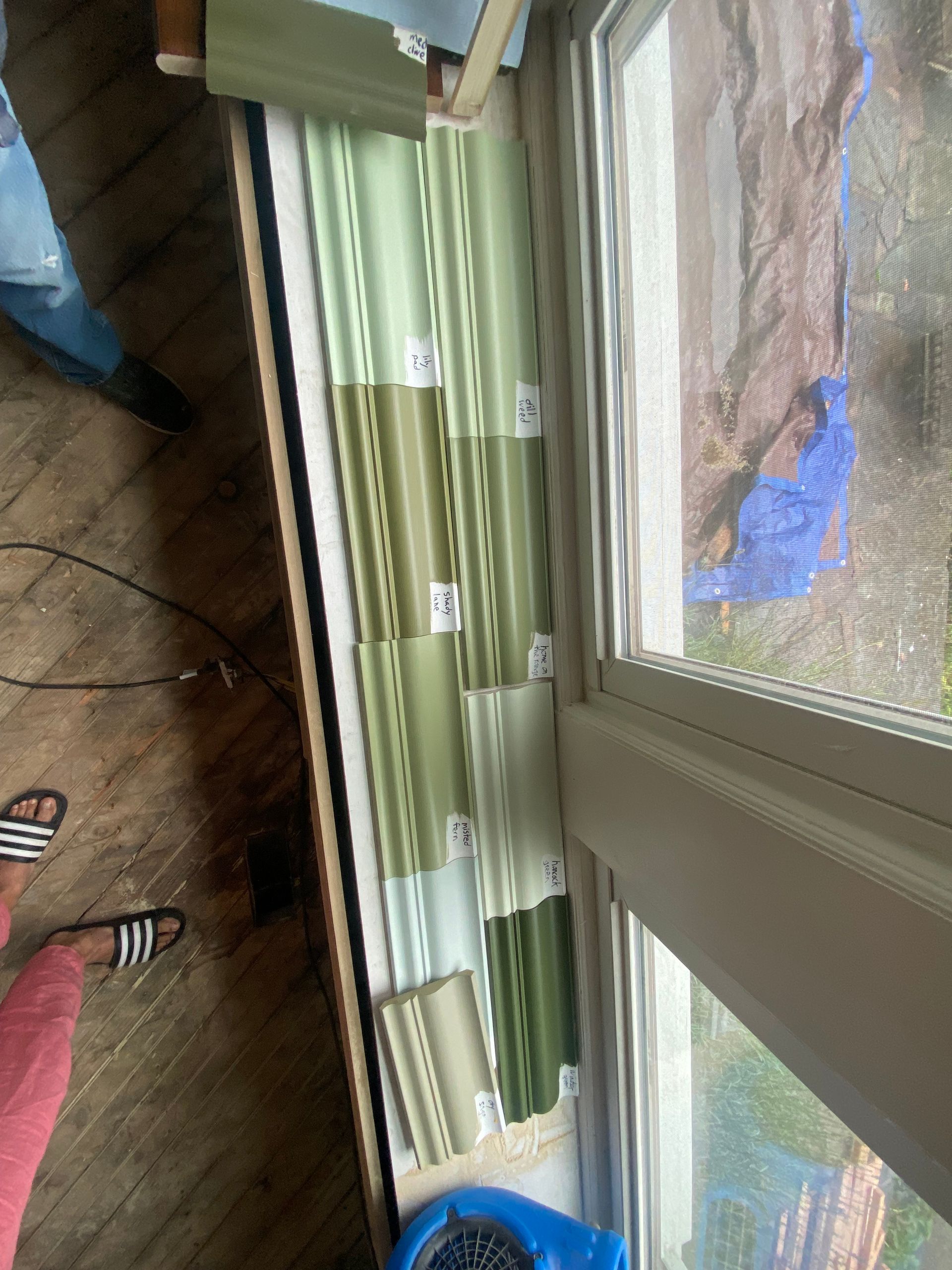 A person is standing in front of a window with curtains on it.