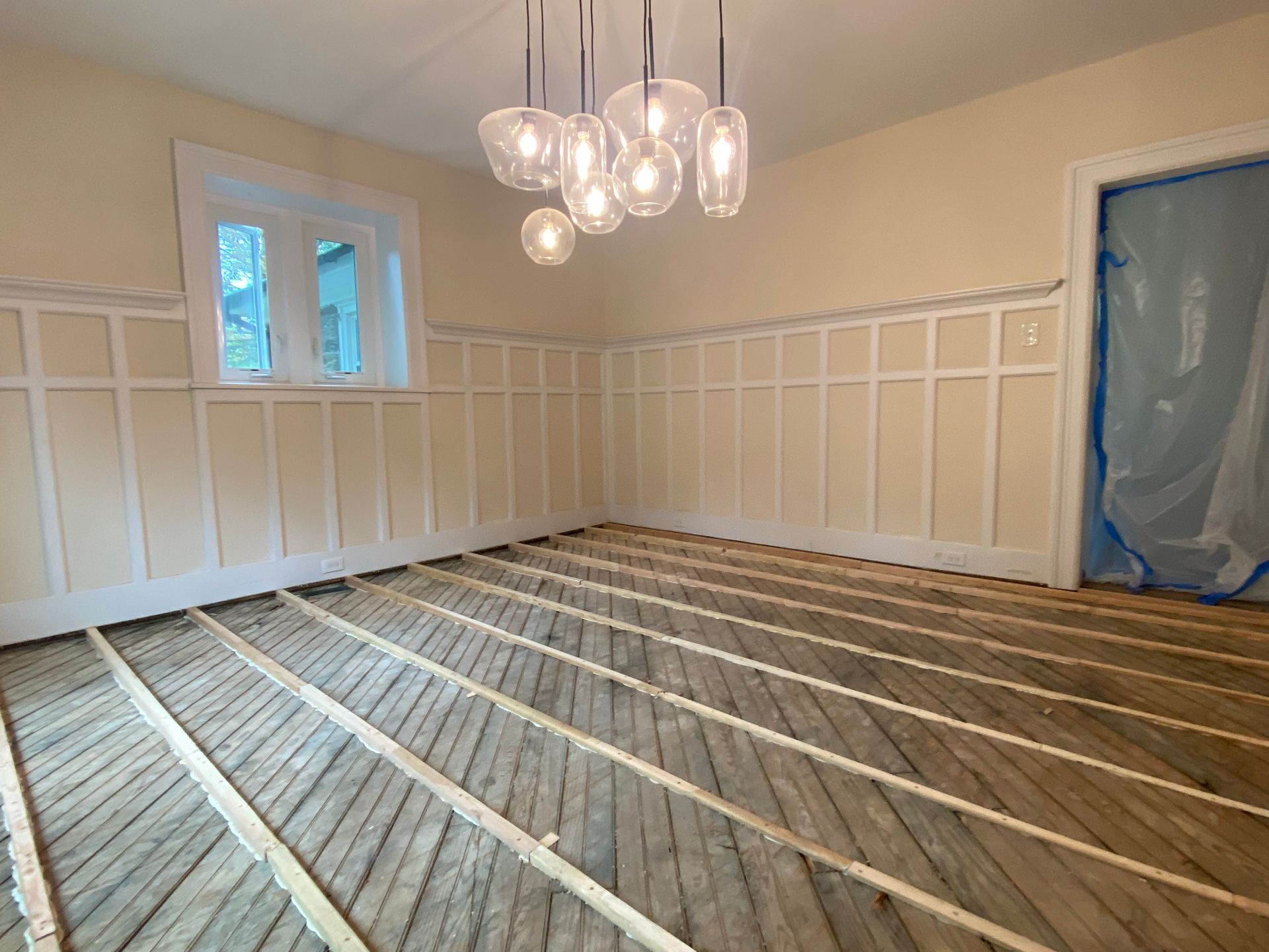 A room with a wooden floor and a chandelier hanging from the ceiling.