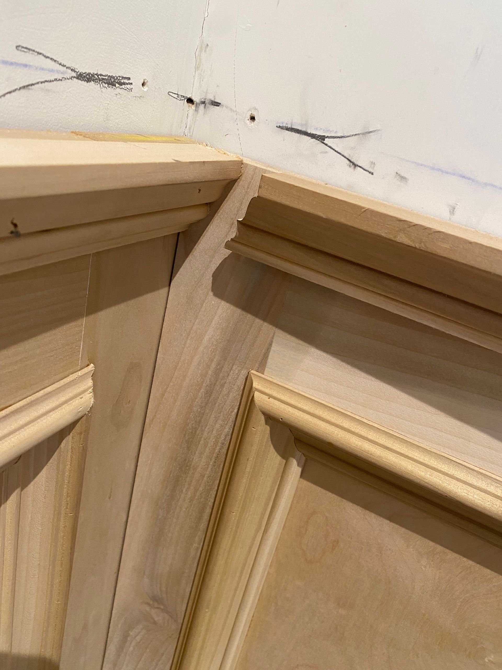 A close up of a wooden door with a white wall in the background.