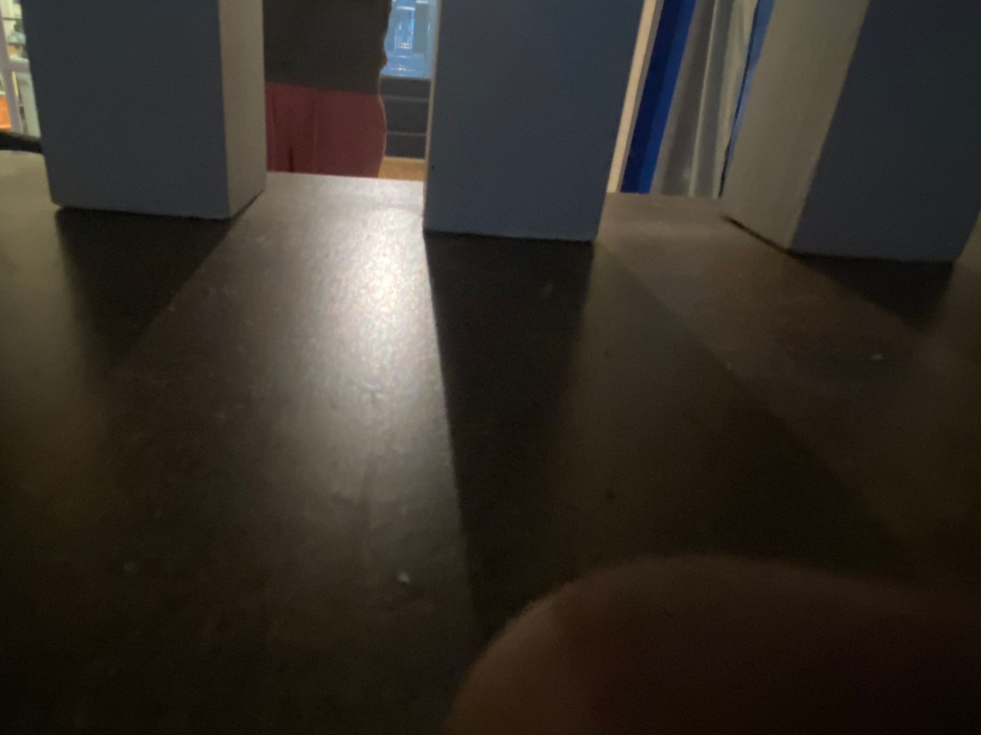 A person is standing on a wooden floor in a dark room.