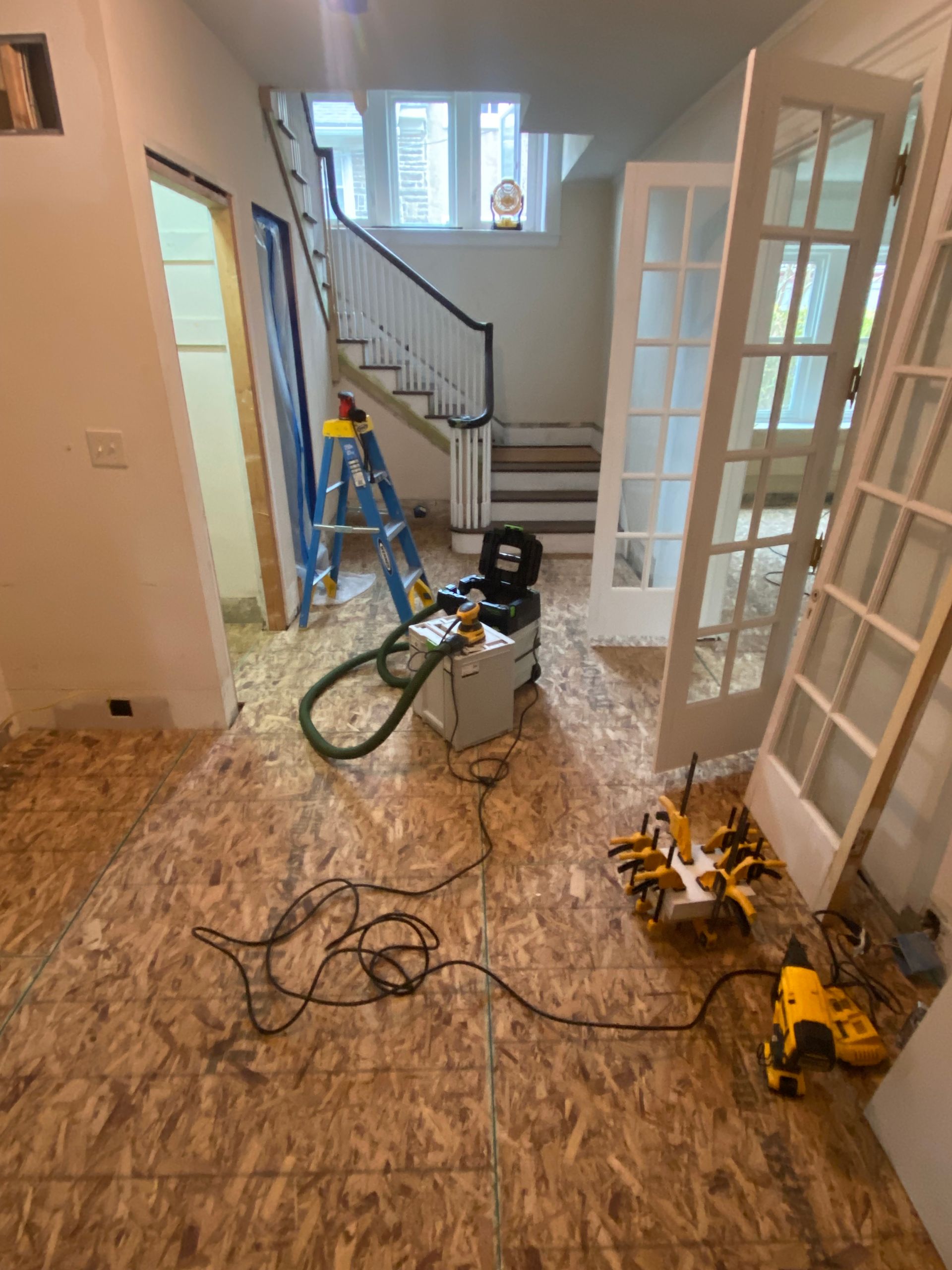 A room with french doors and a vacuum cleaner on the floor
