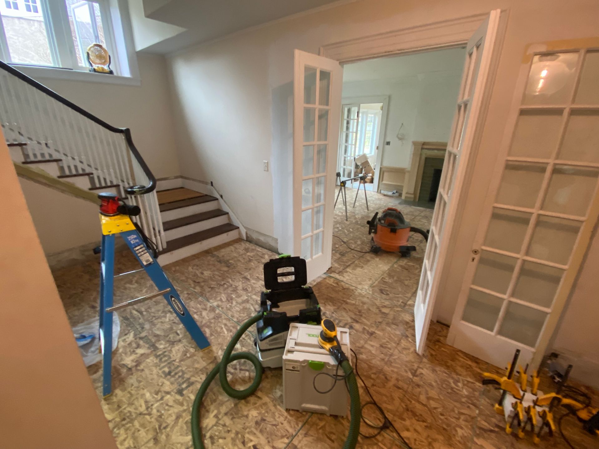 A room with a ladder and a vacuum cleaner in it.