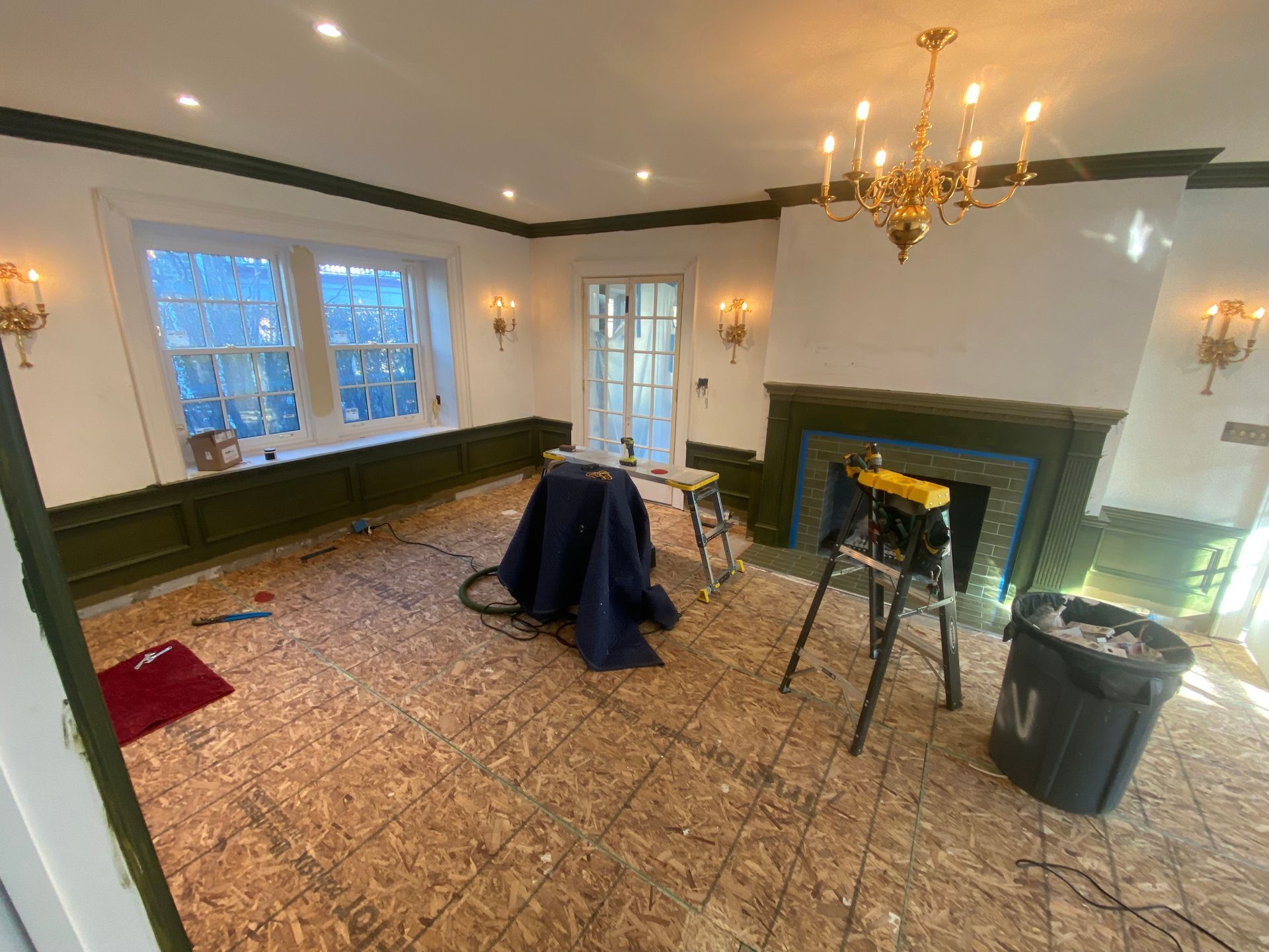 A living room with a fireplace and a ladder in it.