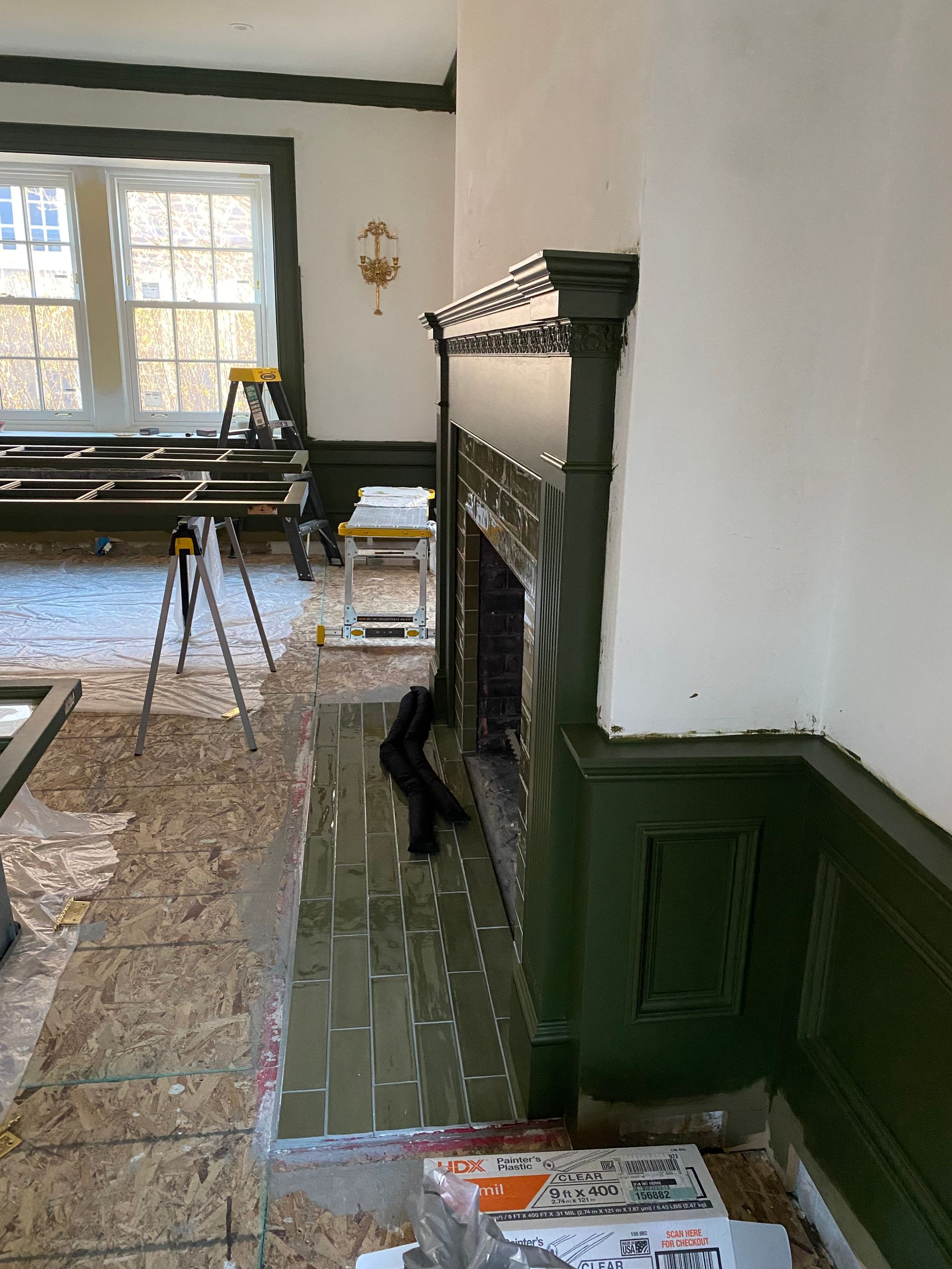 A living room with a fireplace and a ladder in the corner.