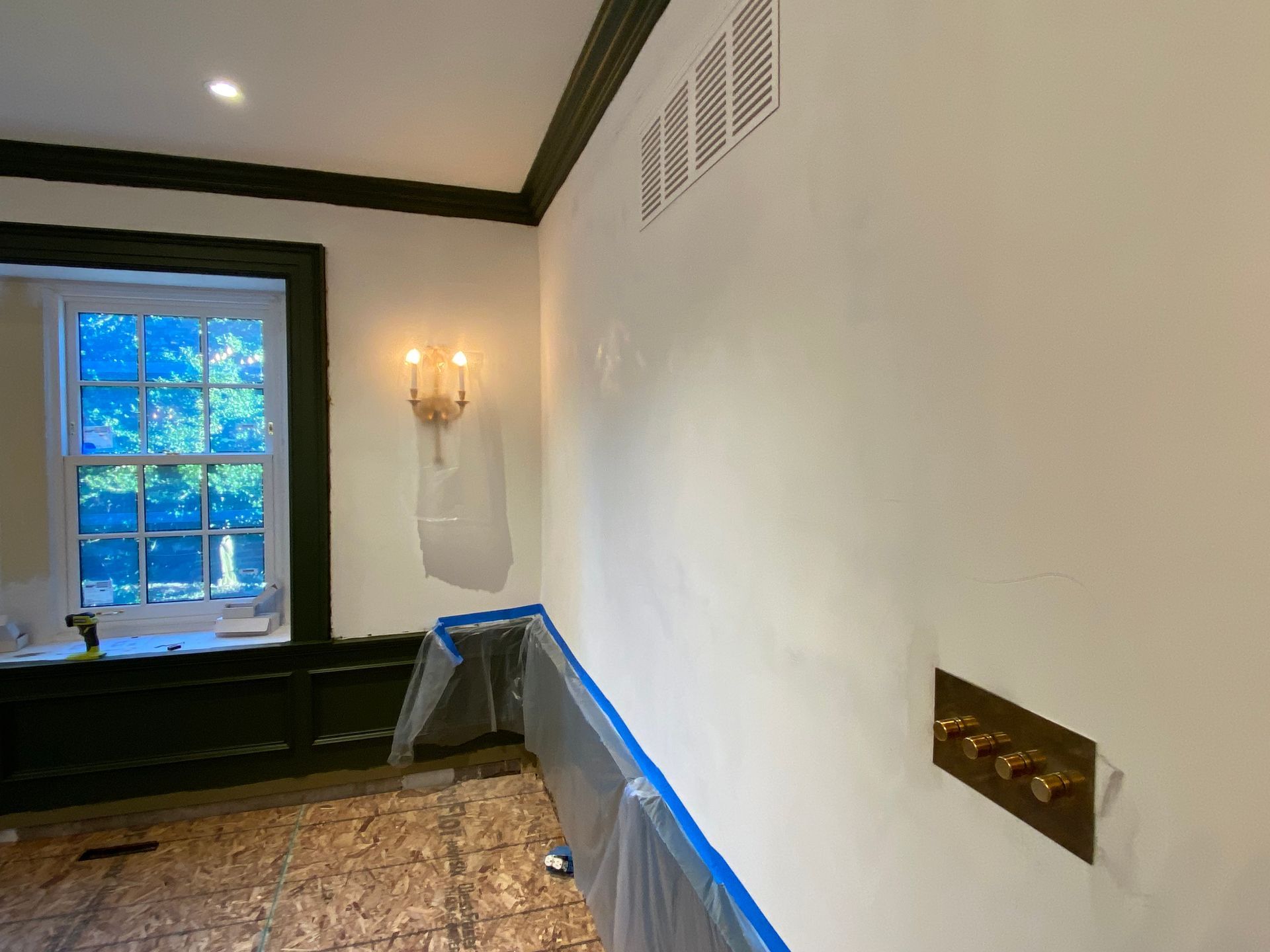 A bathroom with white walls and black trim is being painted