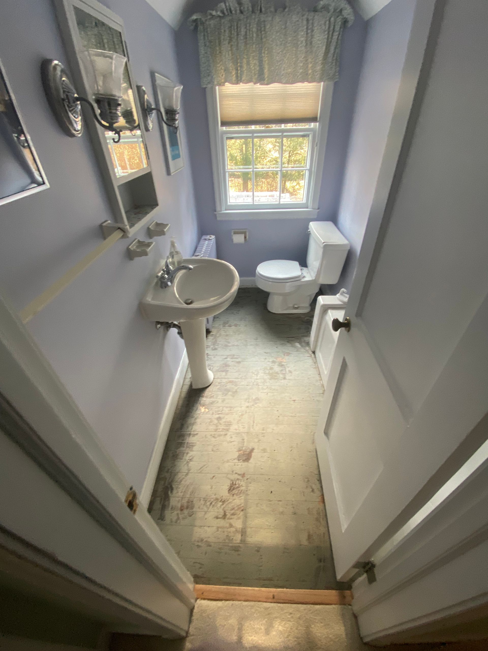 A bathroom with a sink , toilet , mirror and window.