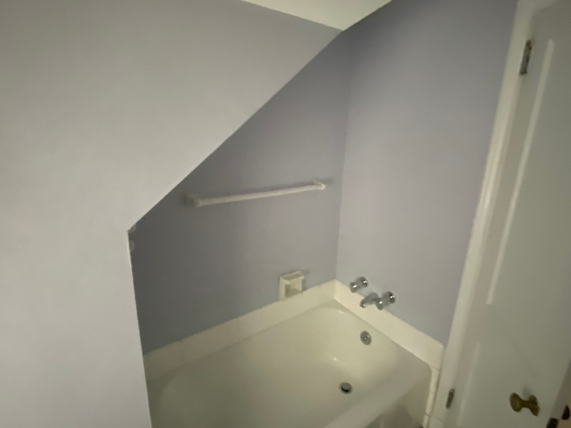 A bathroom with a bathtub under a staircase