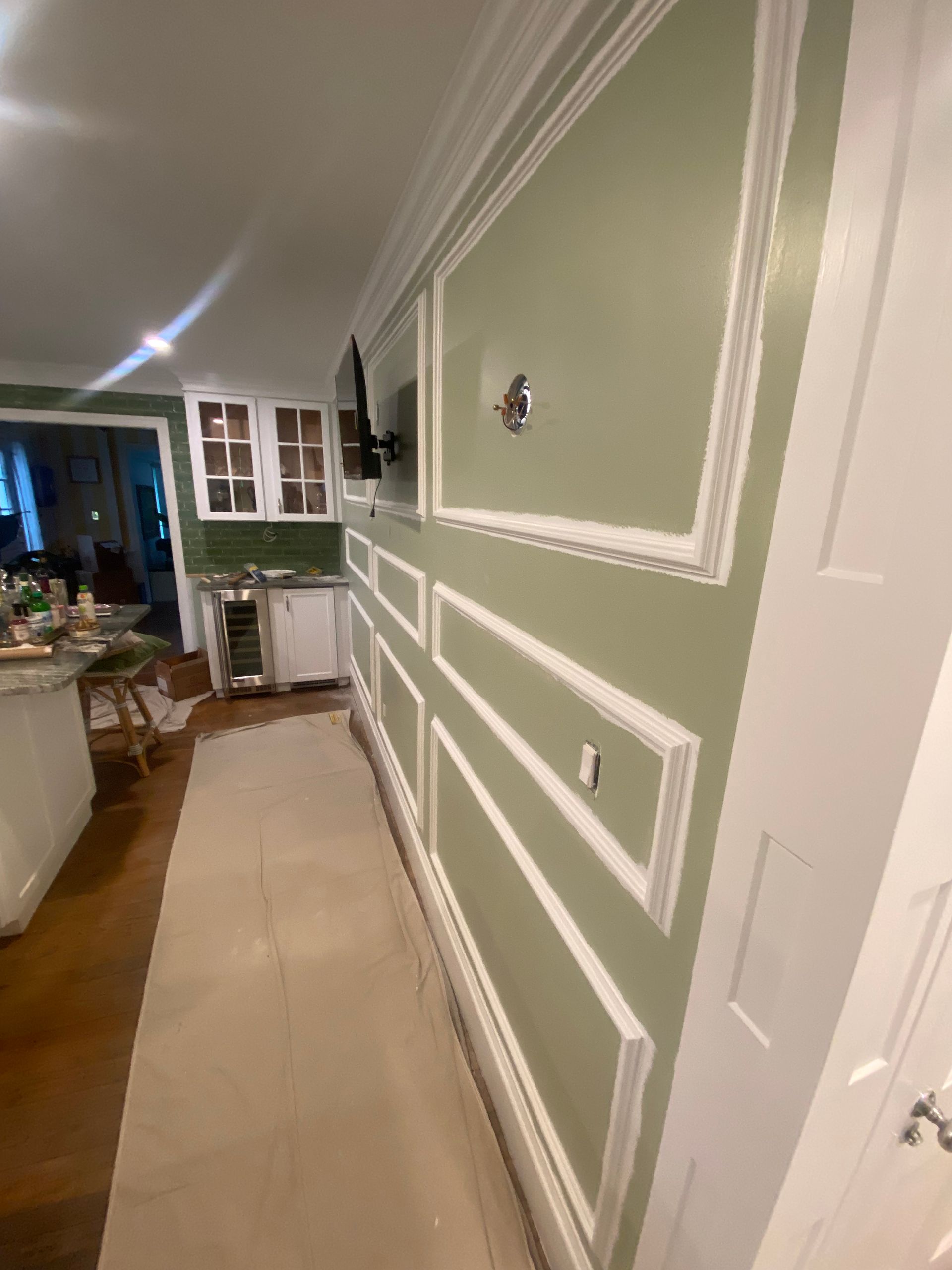 A hallway in a house with green walls and white trim.