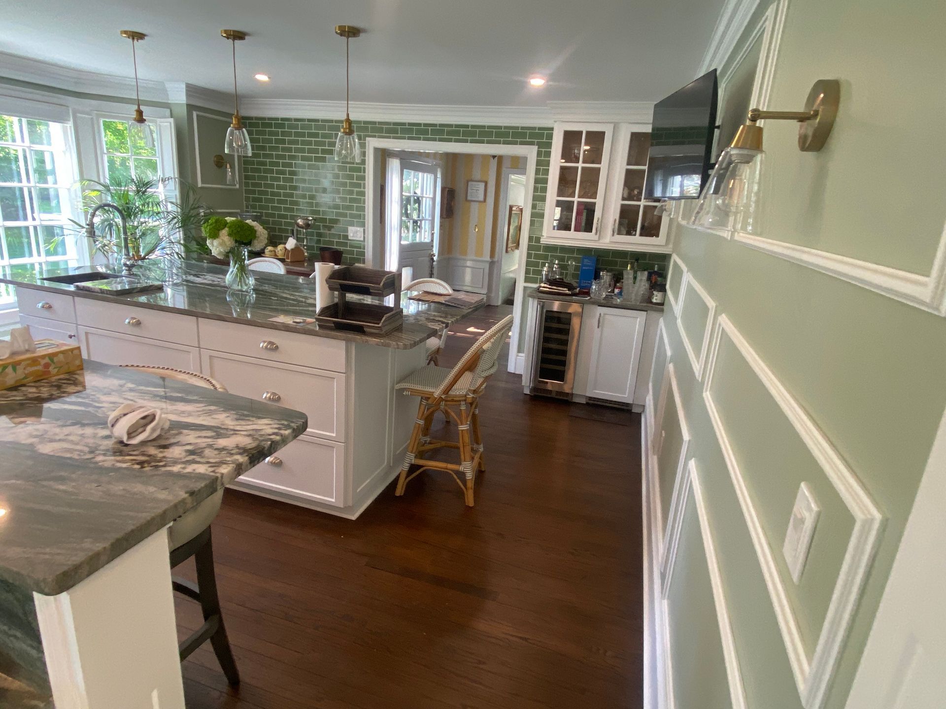 A kitchen with a large island , stools , a refrigerator and a television.