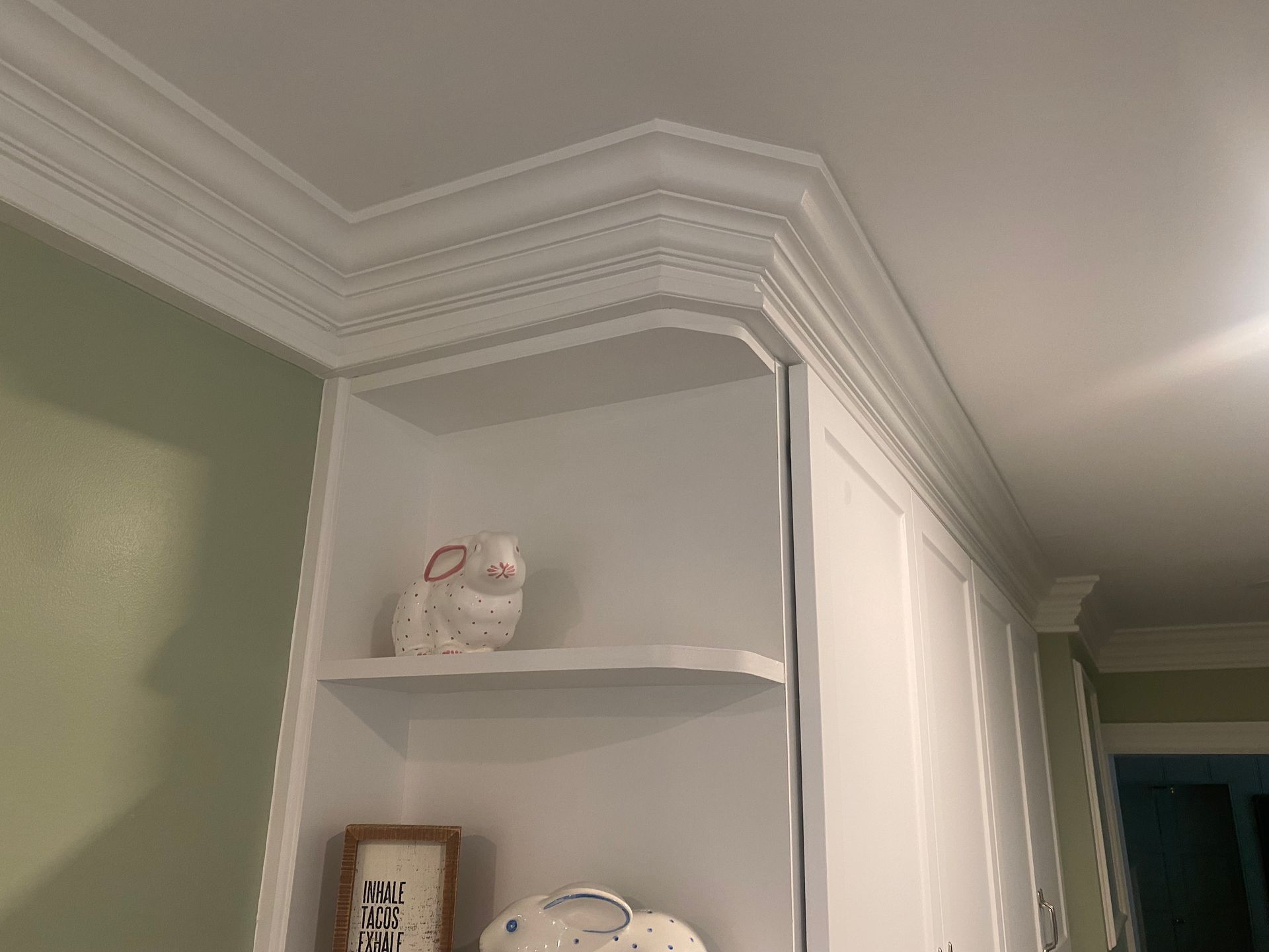 A white shelf with a picture on it in a room with a crown molding.
