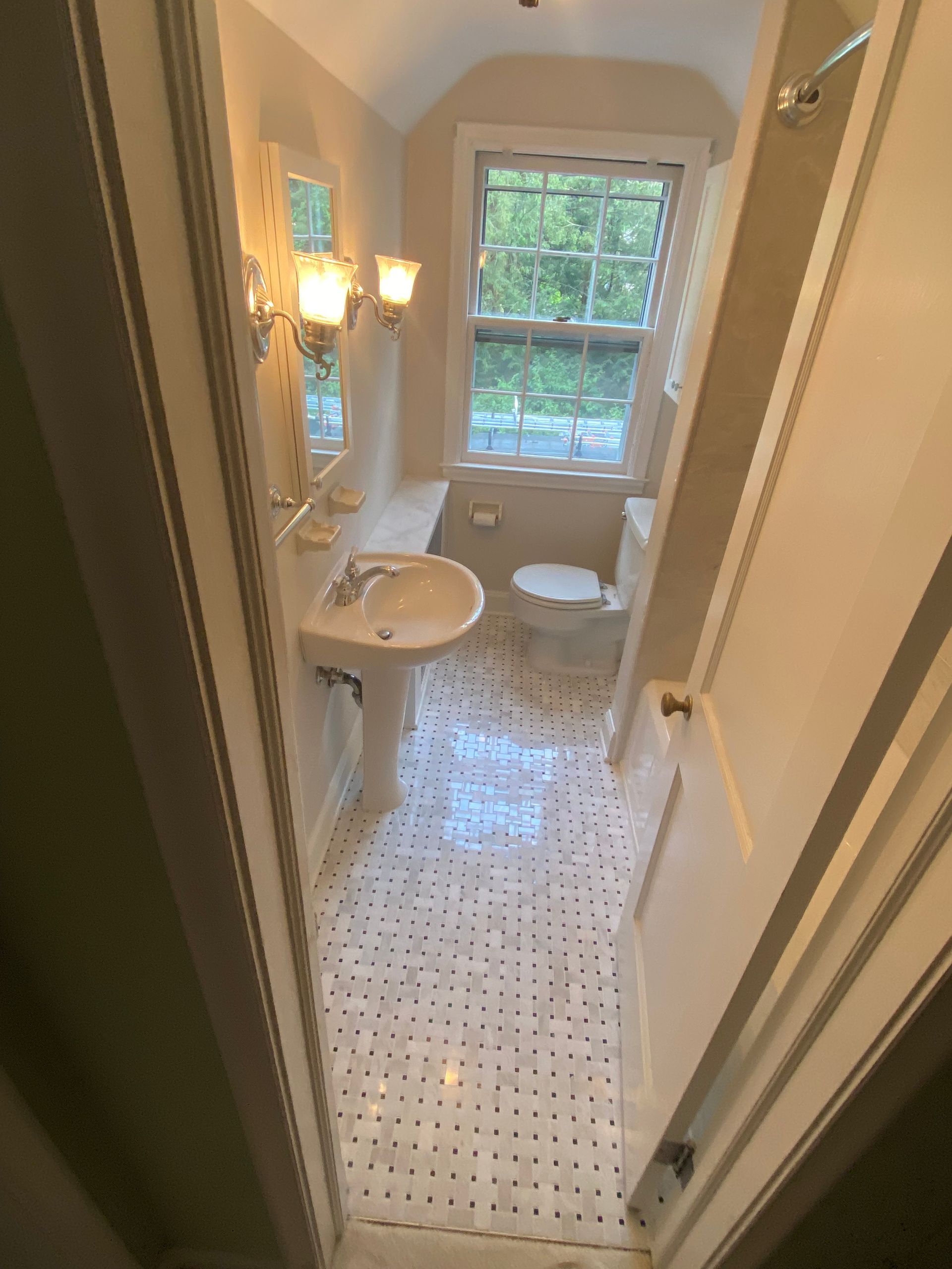 A bathroom with a sink , toilet and window.