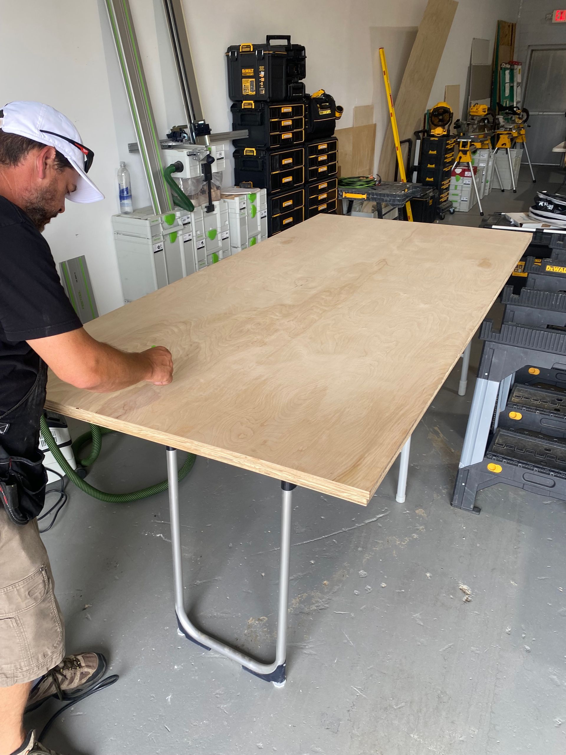 A man is working on a wooden table in a garage