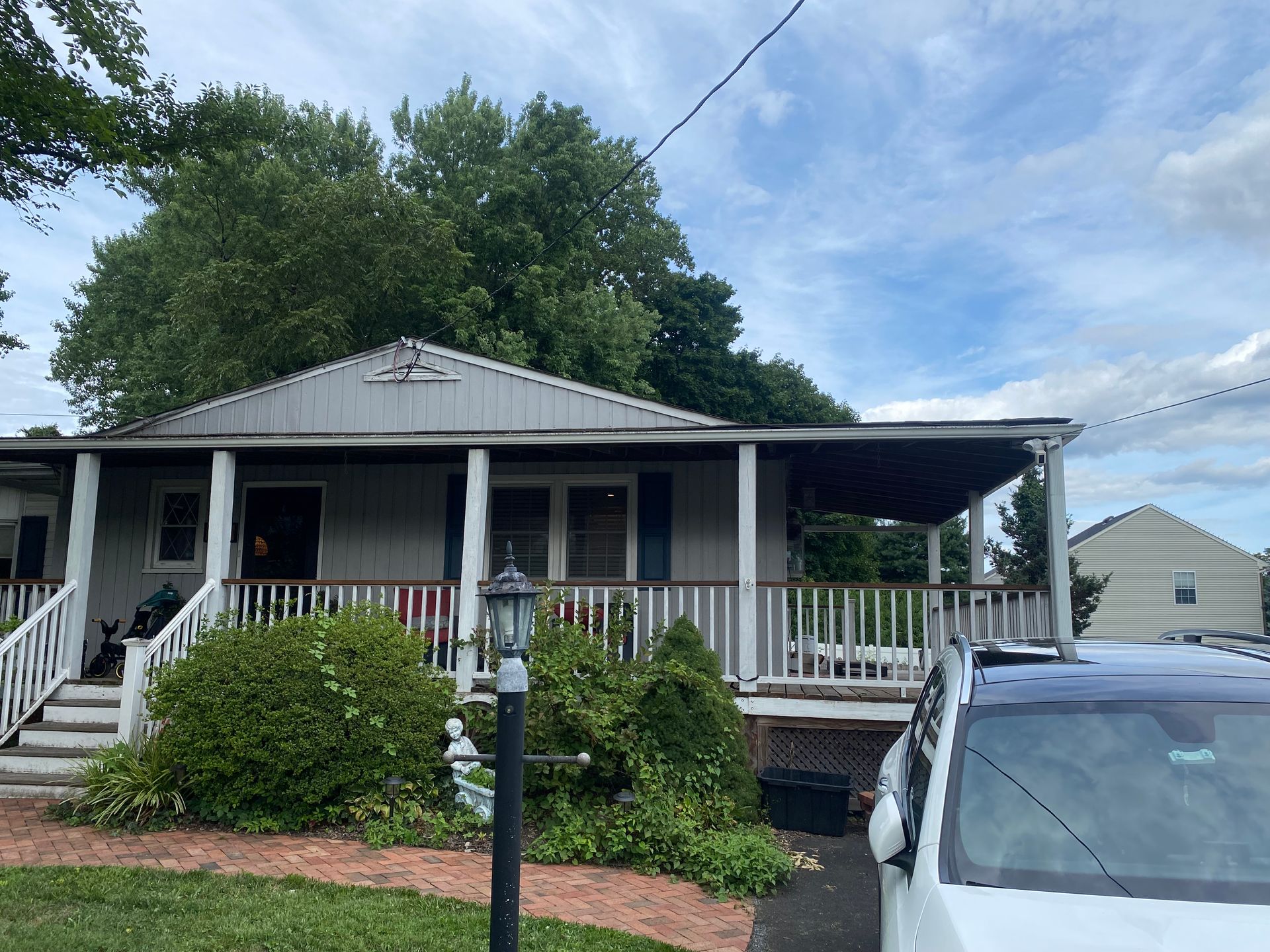A white van is parked in front of a house with a porch.