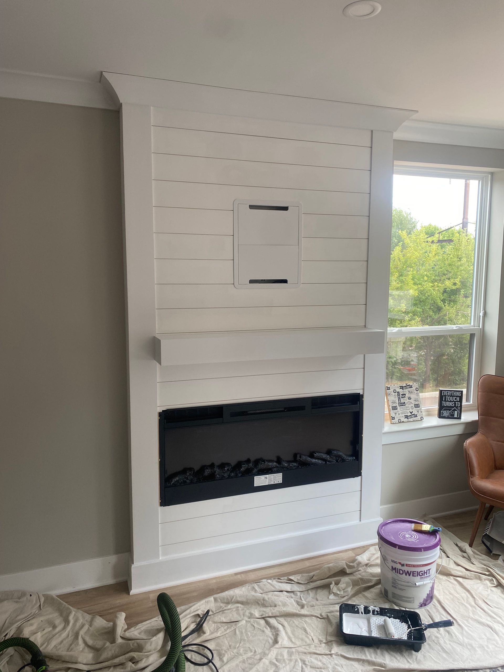 A fireplace is being painted in a living room