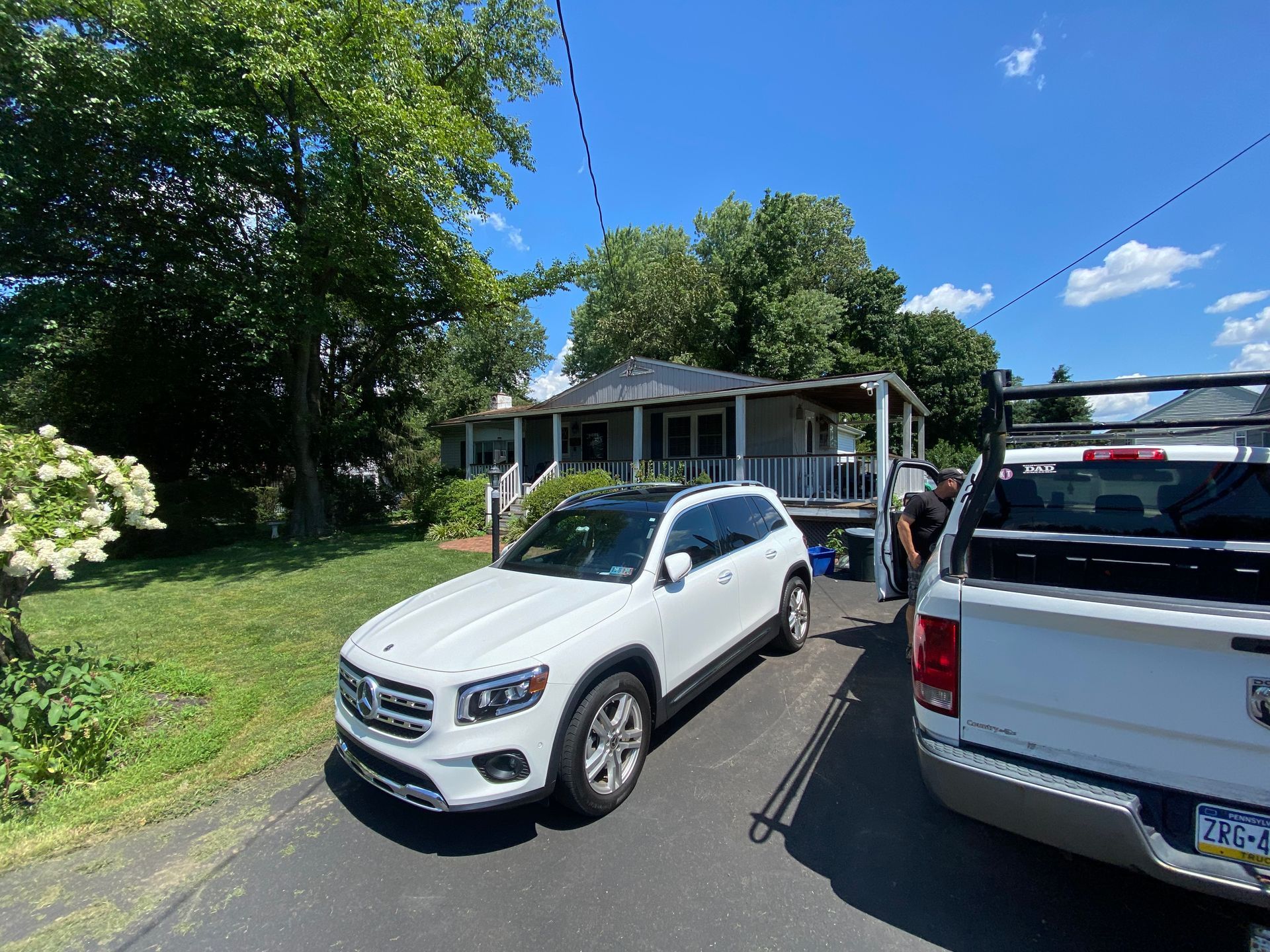 A white suv is parked on the side of the road in front of a house.