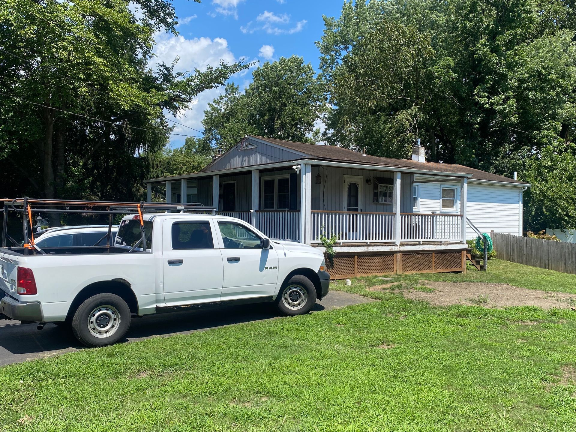 A white truck is parked in front of a house with a porch.