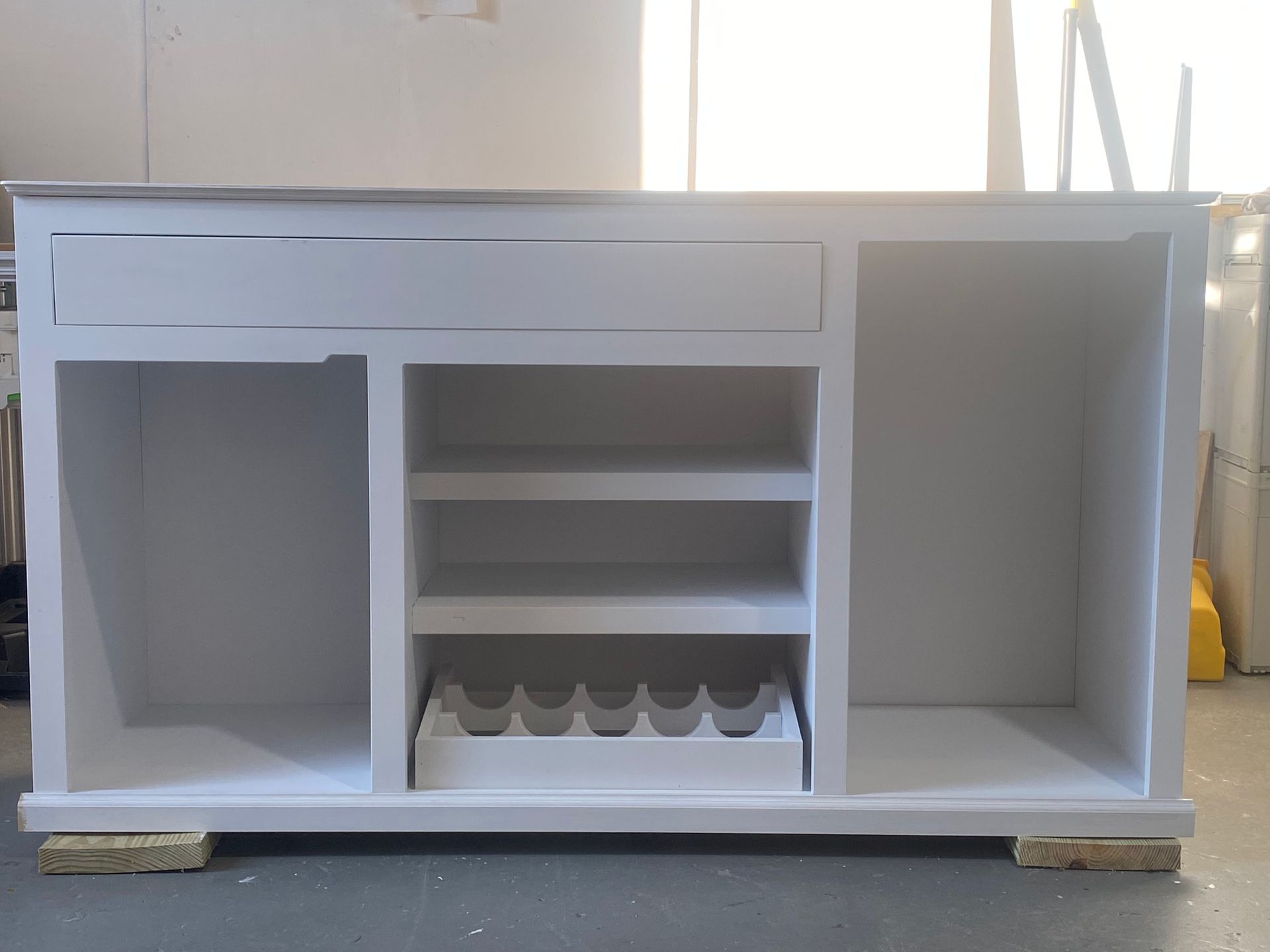A white cabinet with a wine rack on top of it.