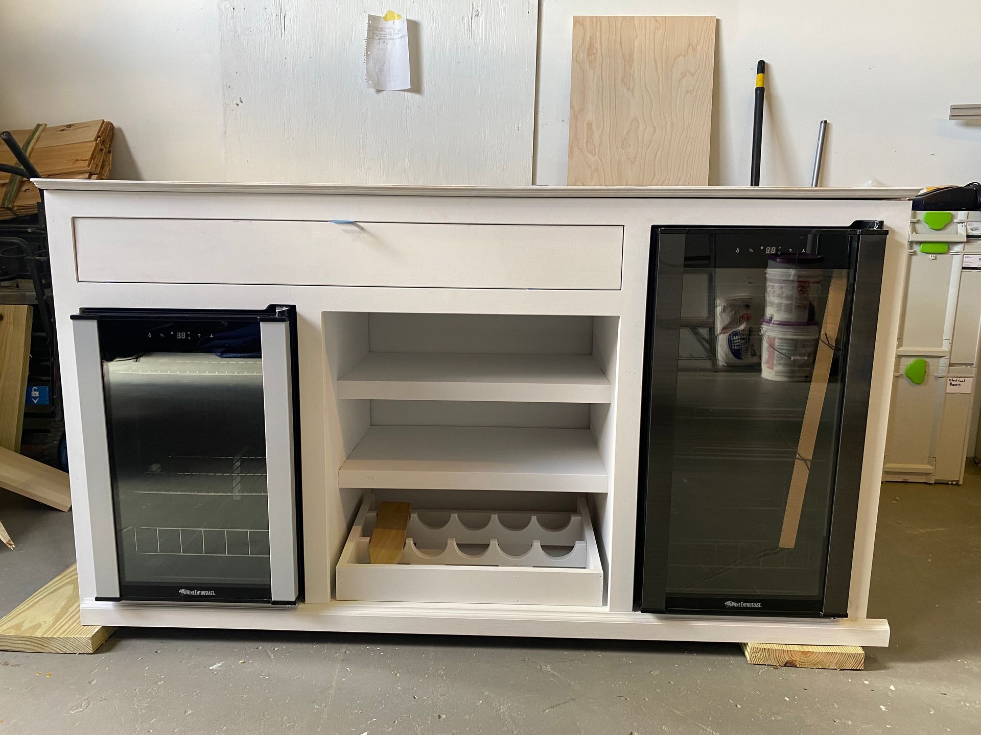 A white cabinet with a wine cooler and a refrigerator.