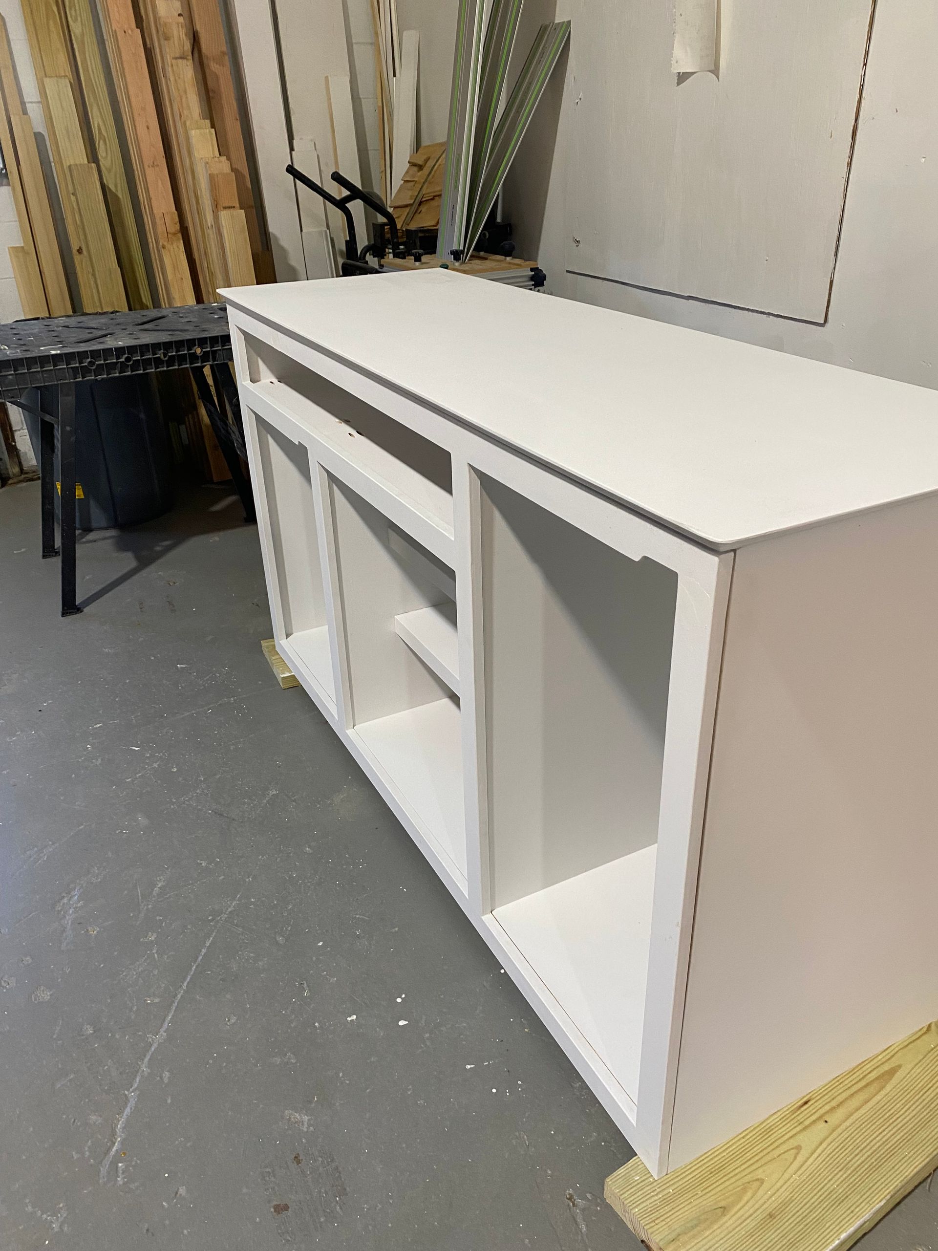 A white cabinet is sitting on a concrete floor in a room.