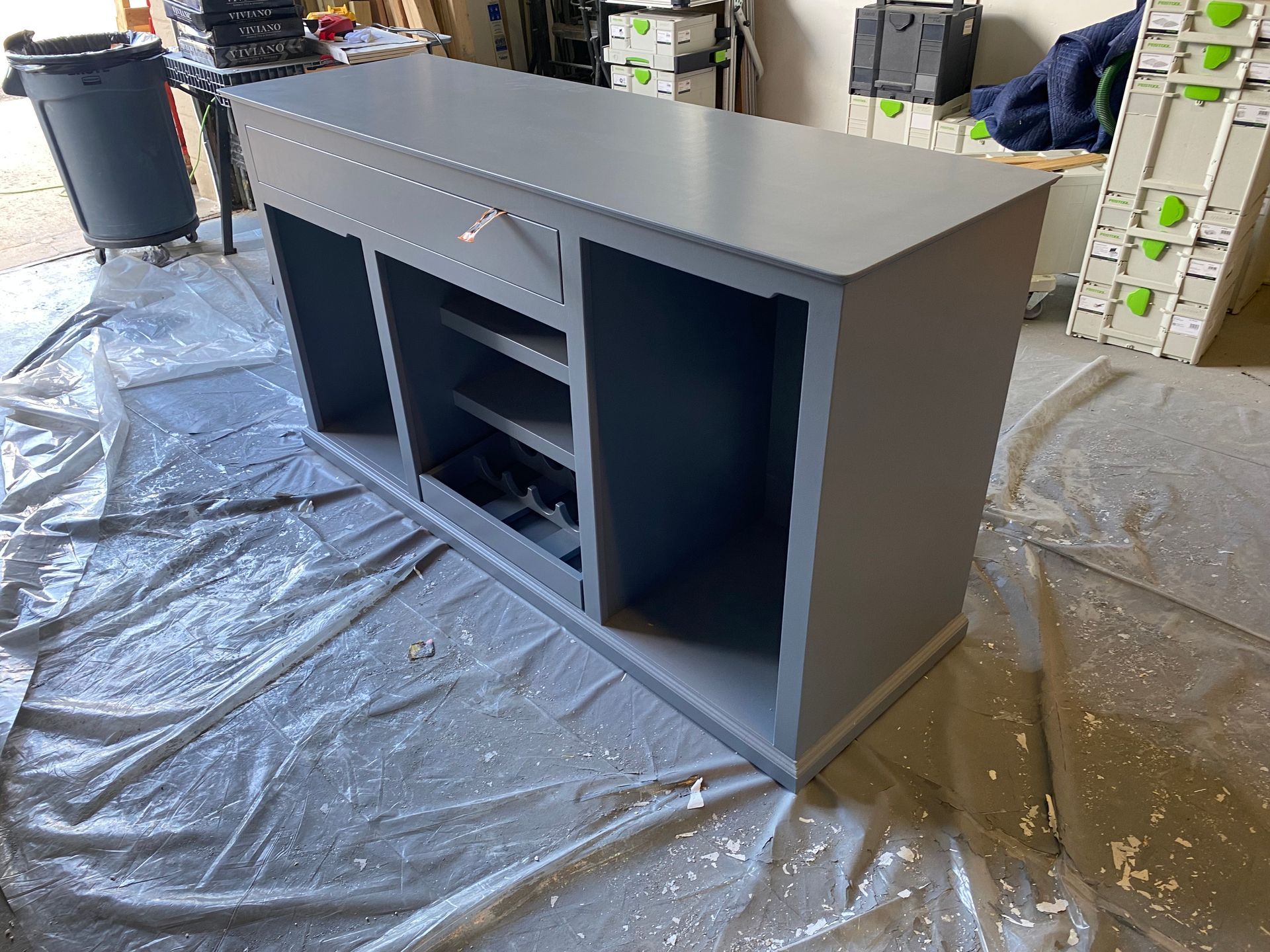 A gray cabinet is sitting on a table in a garage.