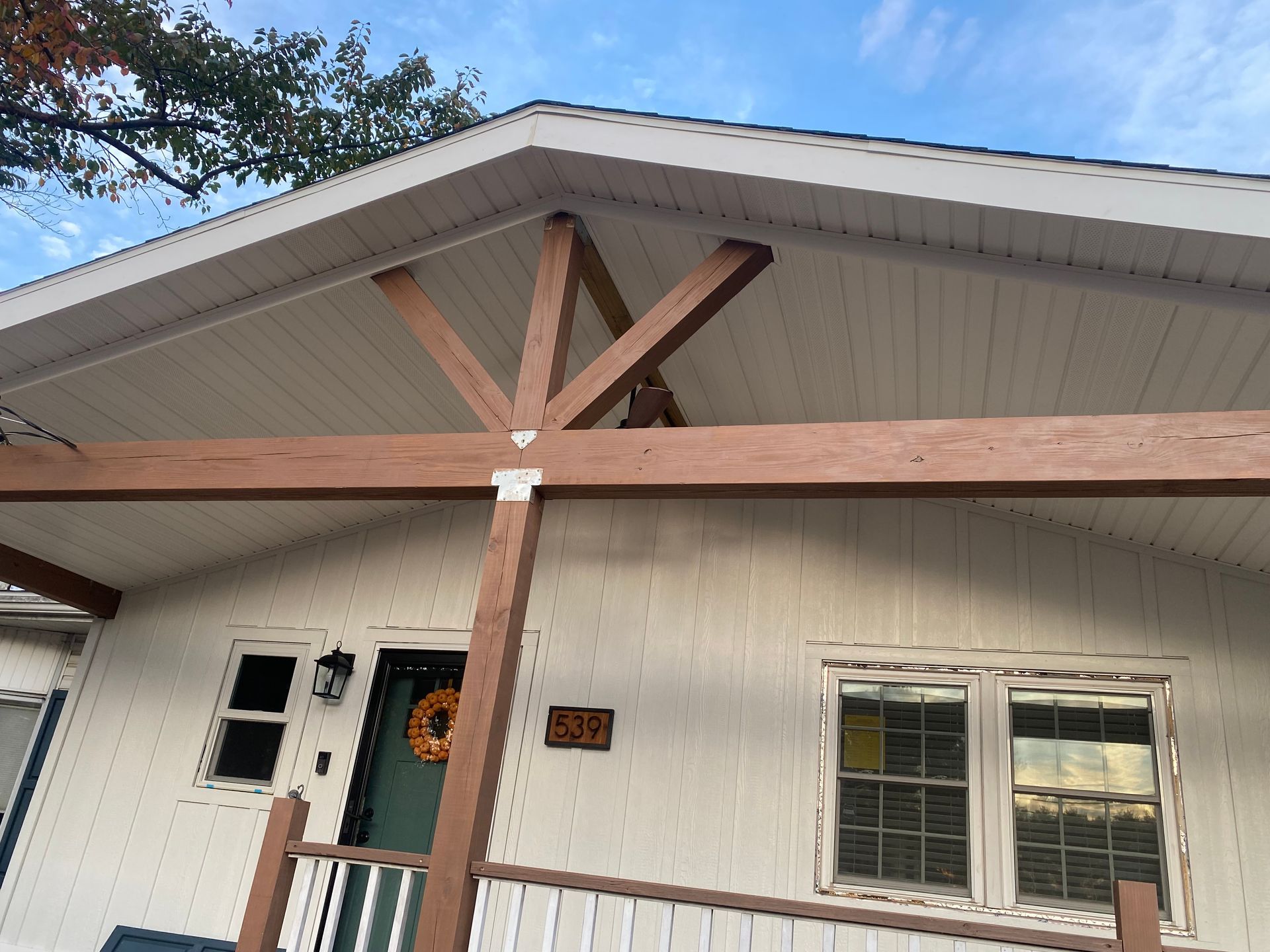 A white house with a wooden porch and a roof