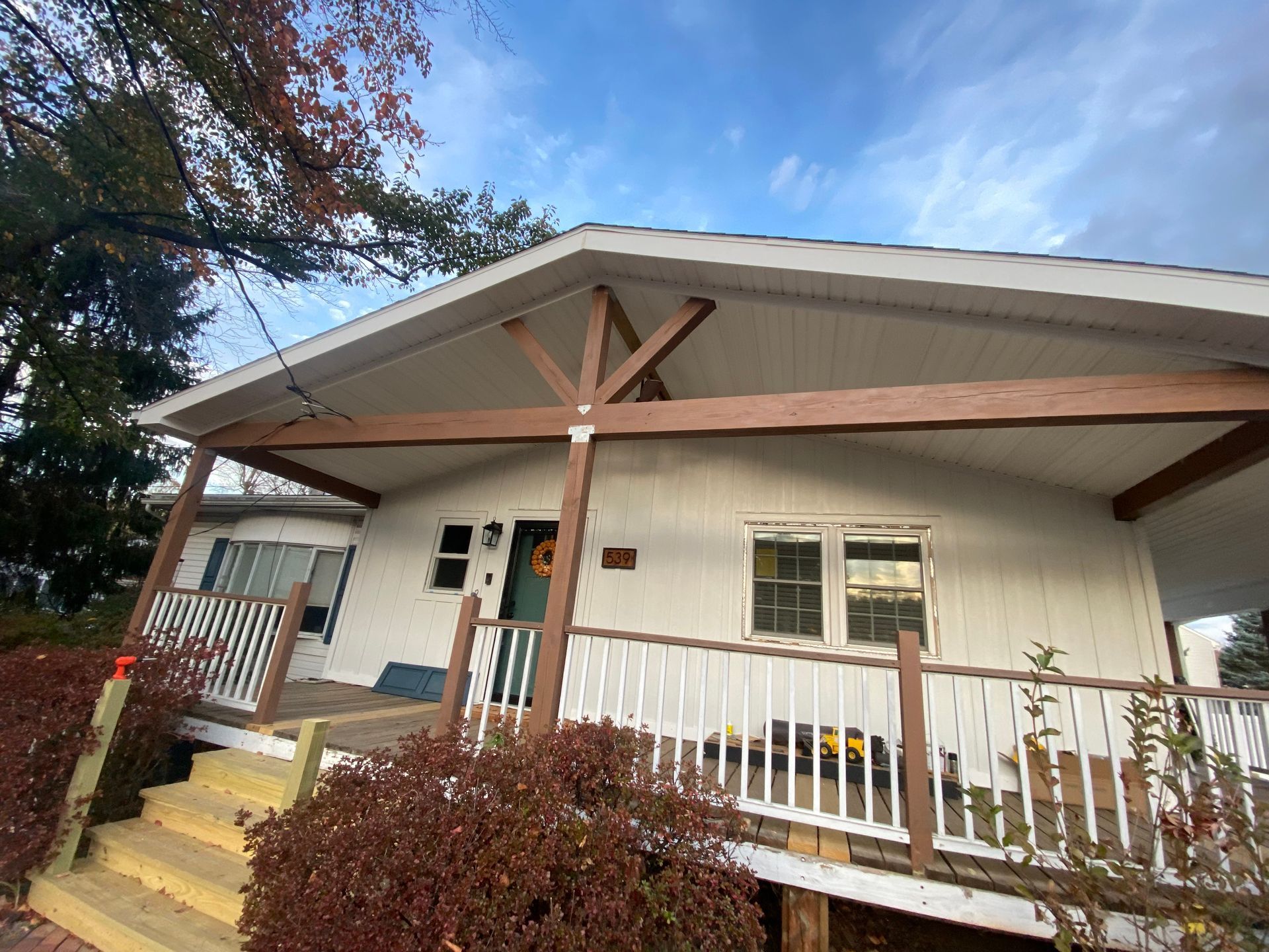 A white house with a wooden porch and stairs.