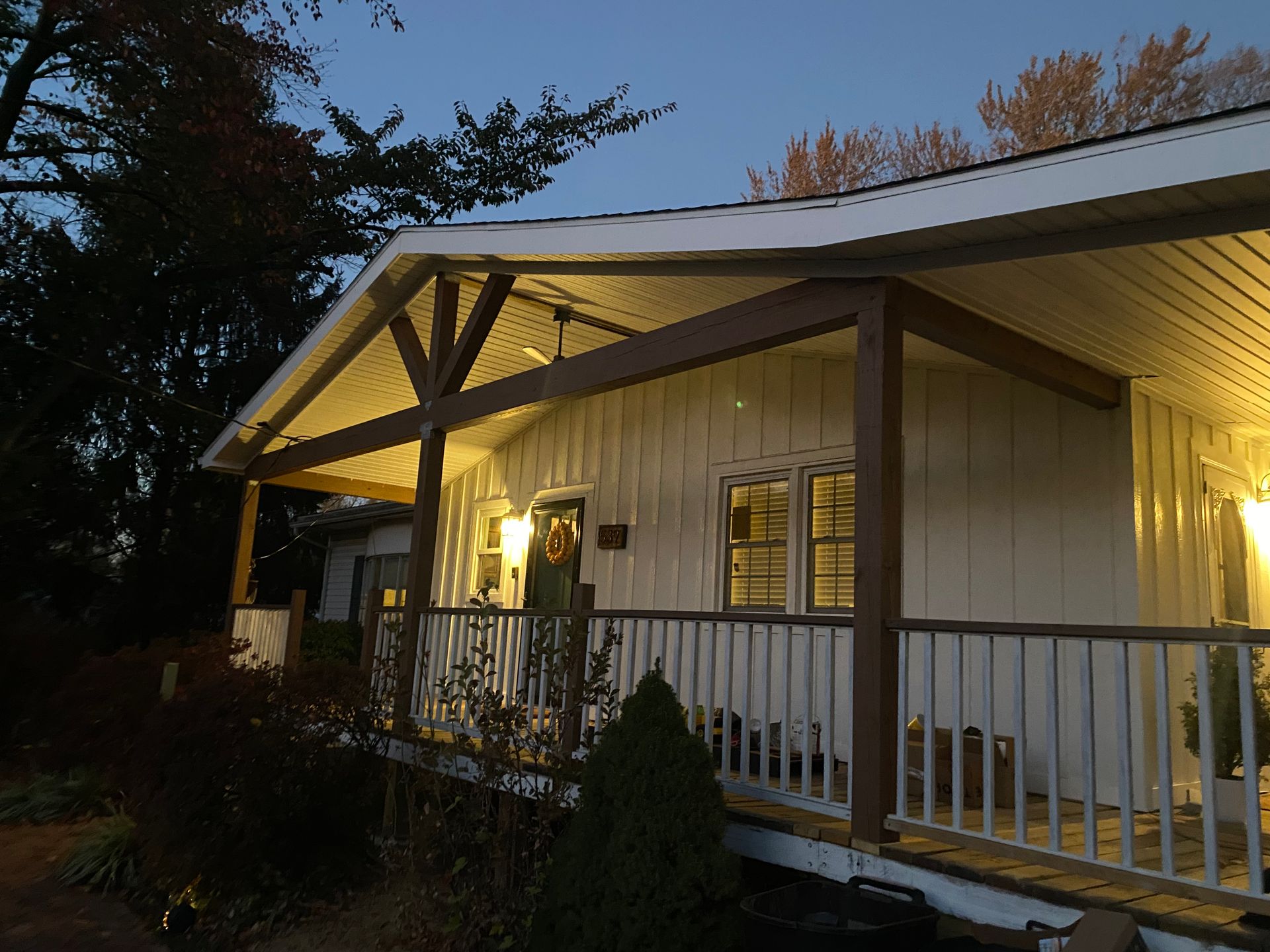 A white house with a porch and trees in the background
