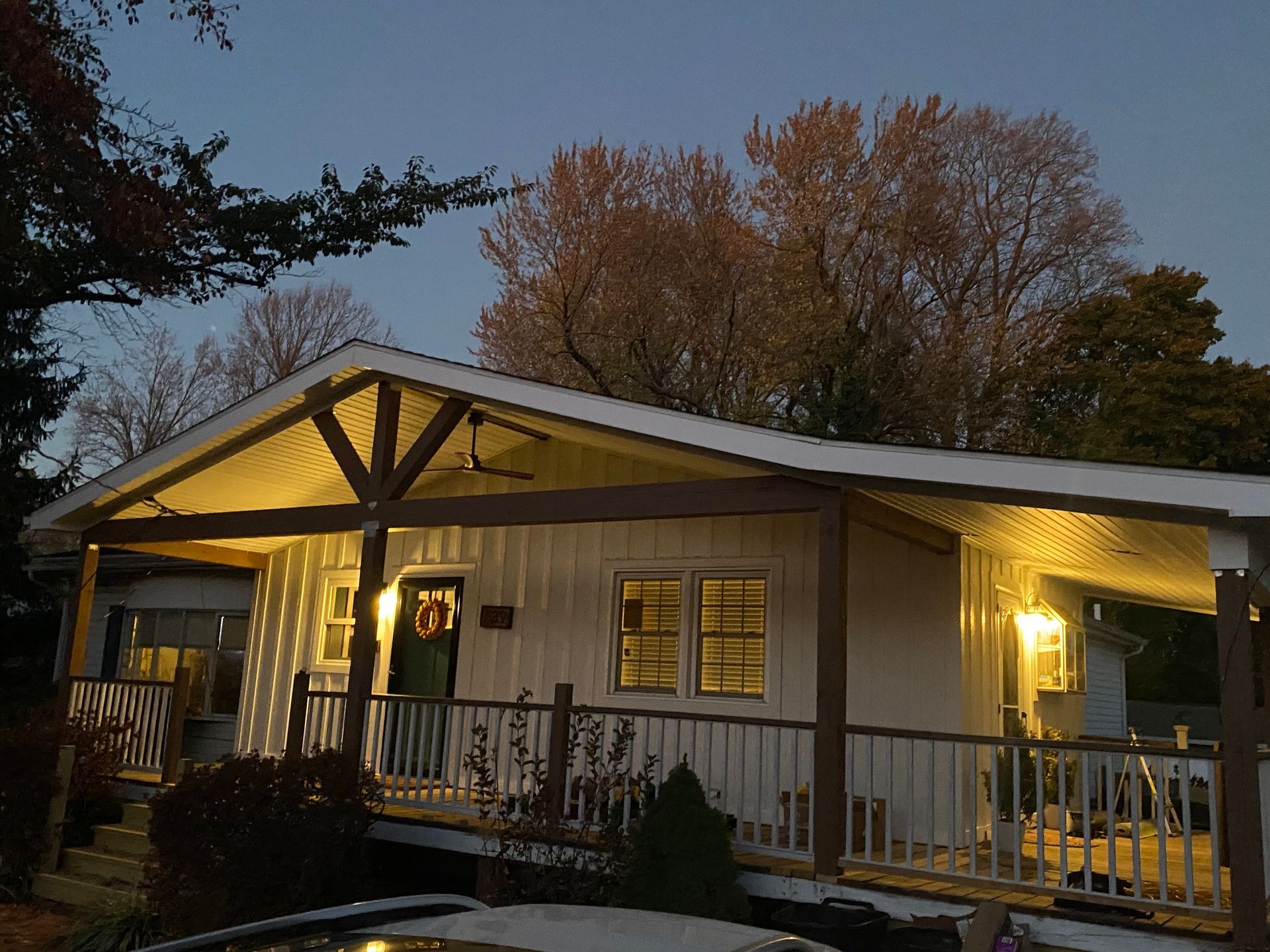 A white house with a porch and trees in the background