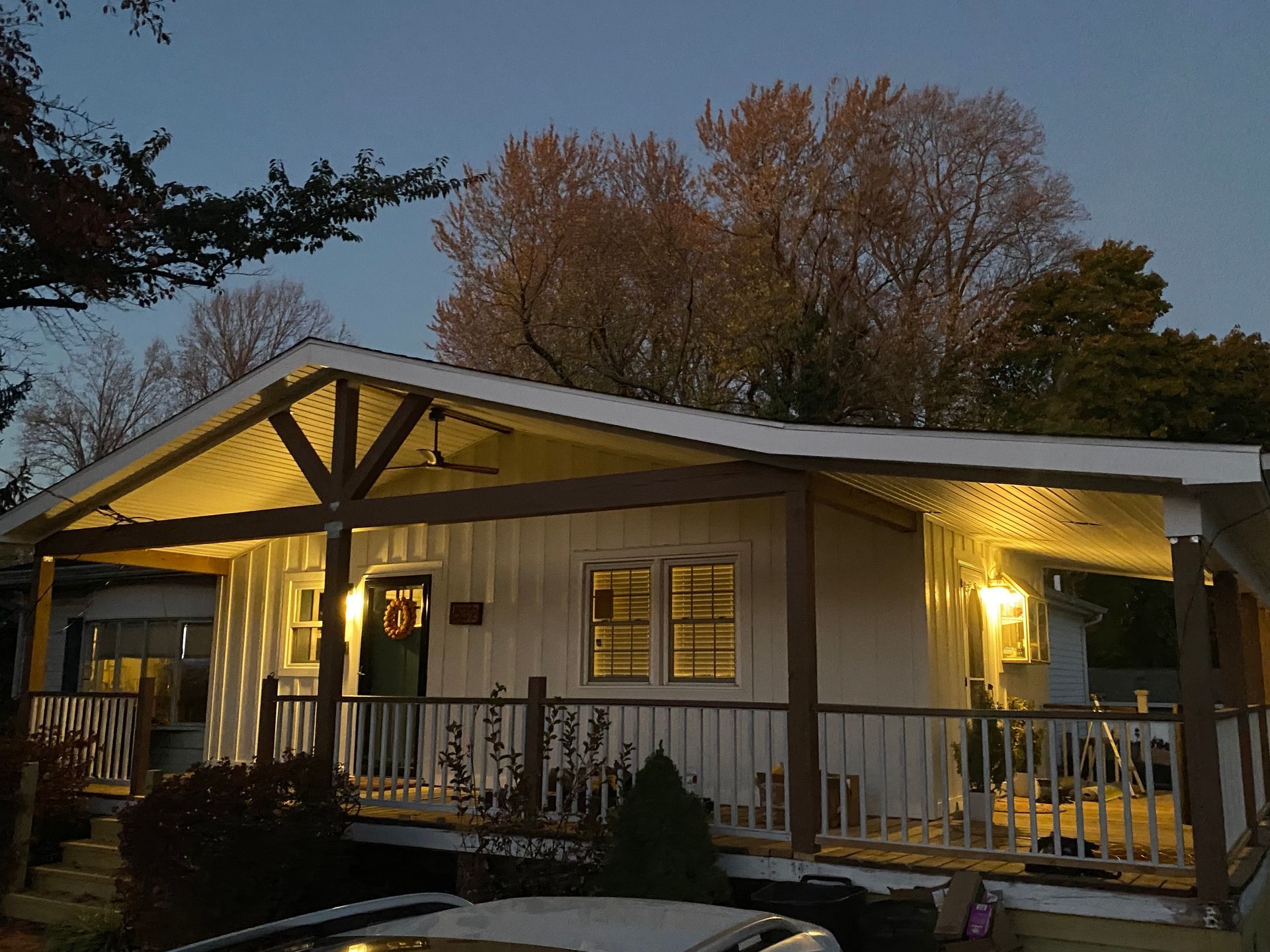 A white house with a porch and a car parked in front of it