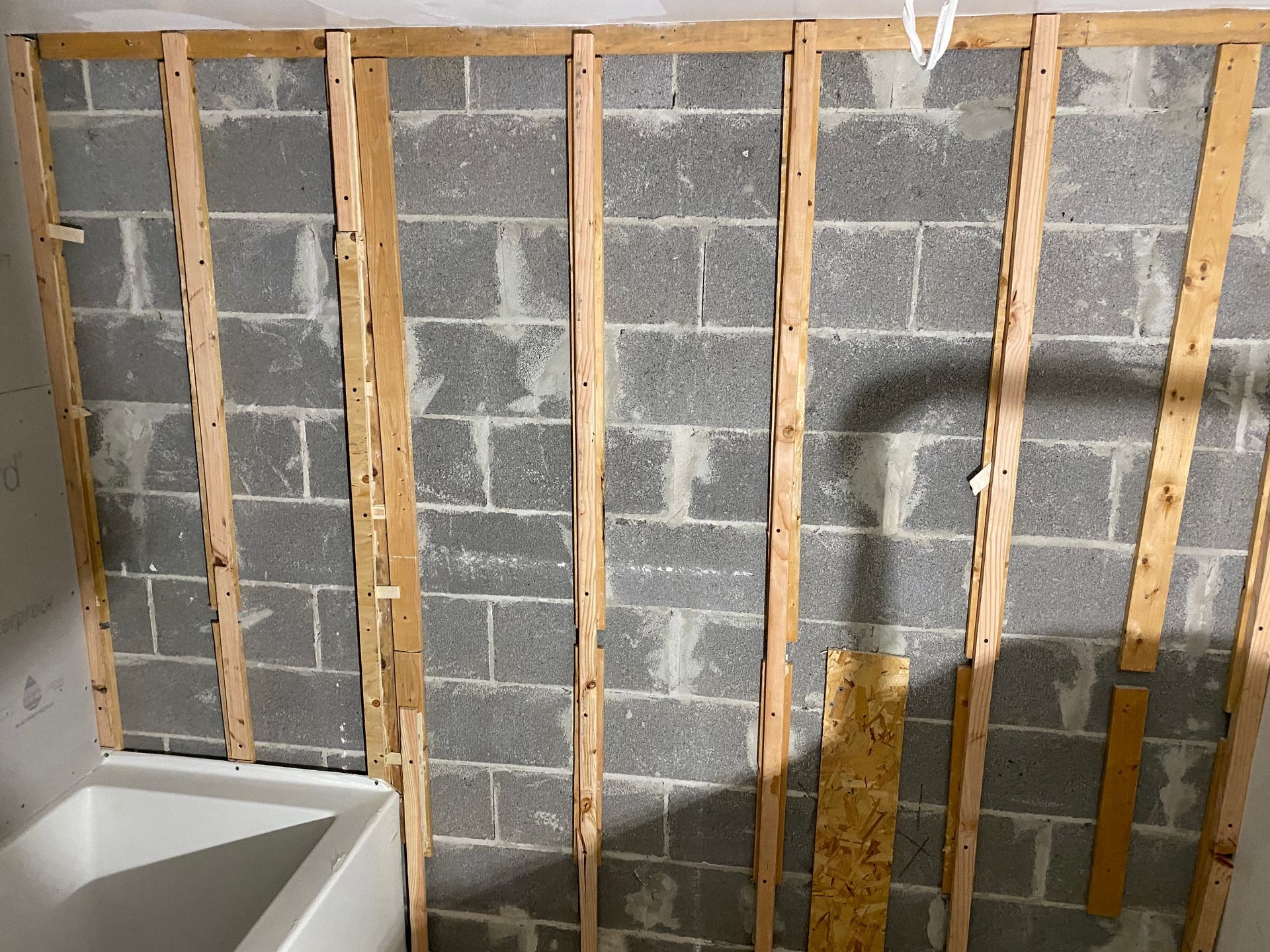 A bathroom with a bathtub and a brick wall with wooden beams.
