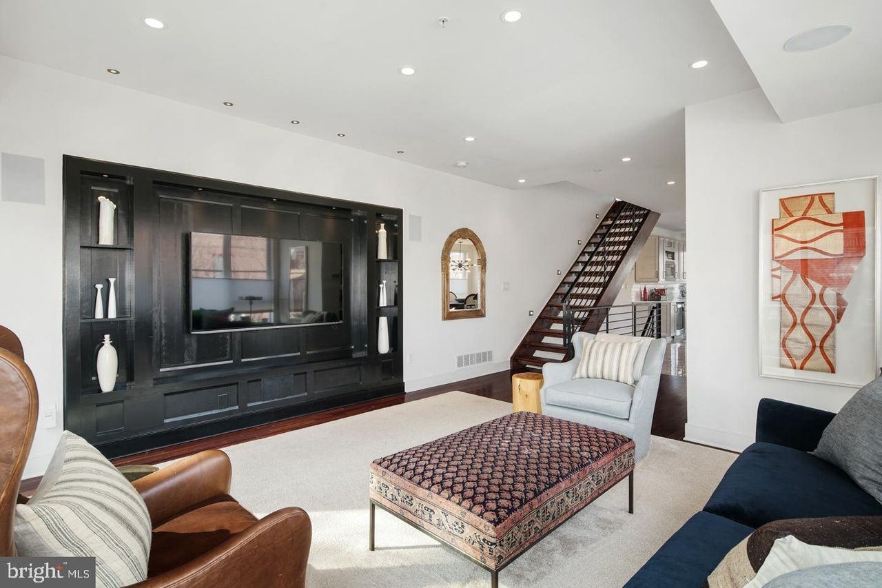 A living room with a couch and chairs and a staircase