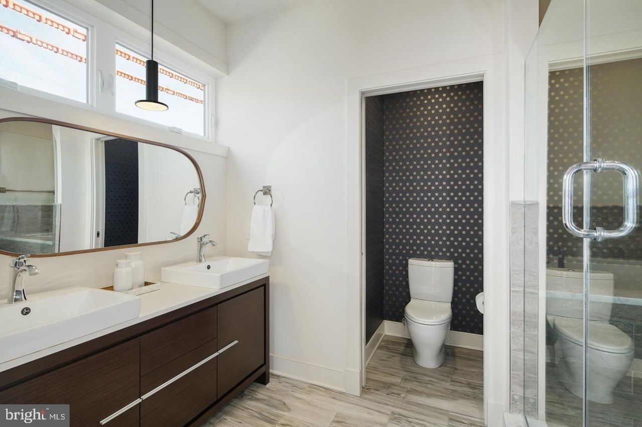 A bathroom with two sinks , a toilet , and a walk in shower.