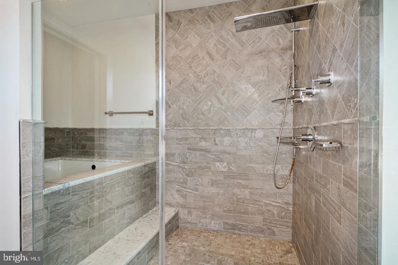 A bathroom with a walk in shower and a tub.