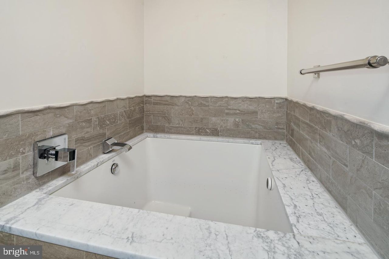 A bathroom with a bathtub and a marble counter top.