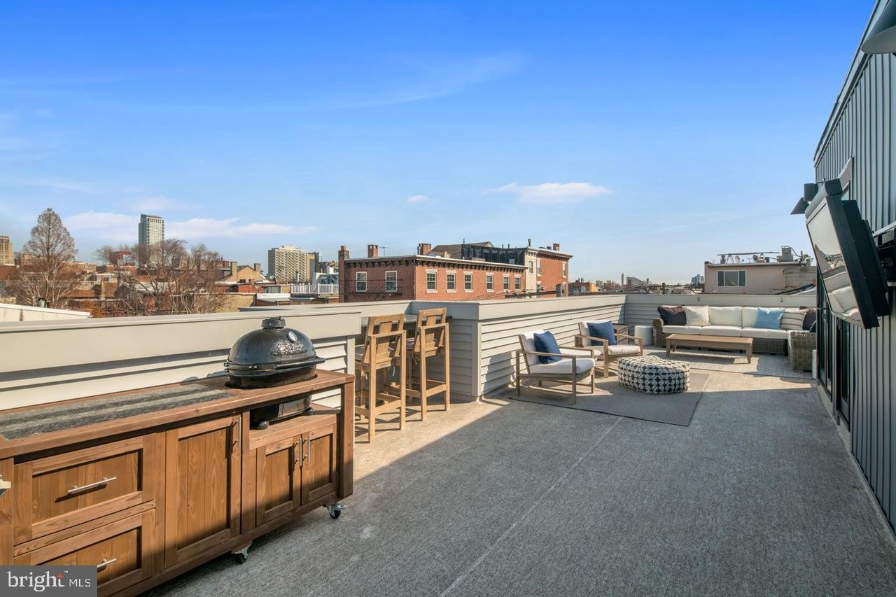 A rooftop deck with a bbq and a flat screen tv.