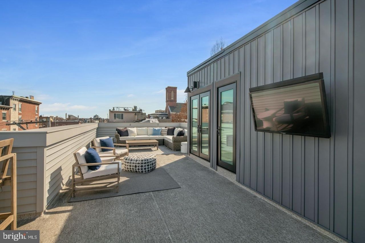 A rooftop deck with a flat screen tv mounted on the wall.