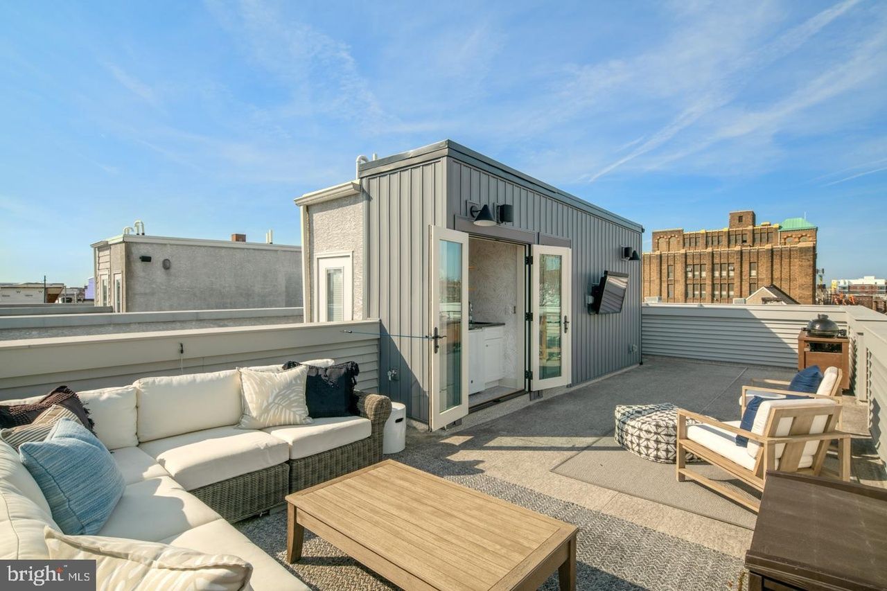 A rooftop deck with a couch , chairs , and a coffee table.