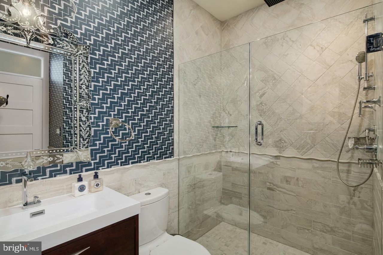 A bathroom with a toilet , sink , shower and mirror.