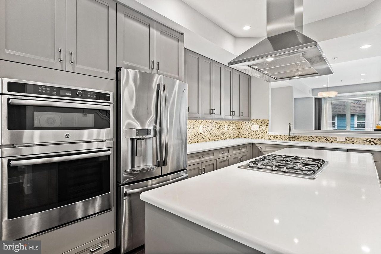 A kitchen with stainless steel appliances and gray cabinets.
