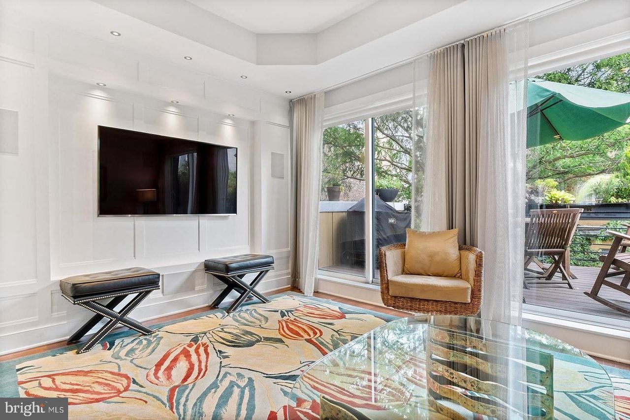 A living room with a flat screen tv on the wall and a glass coffee table.