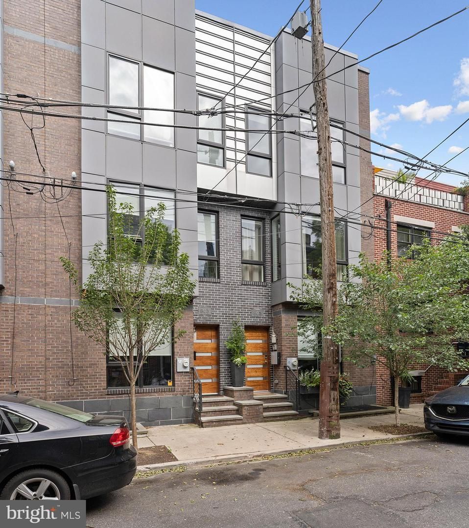A black car is parked in front of a large building