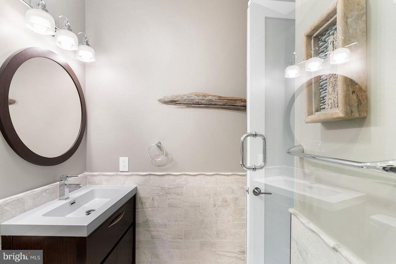 A bathroom with a sink , mirror and shower.