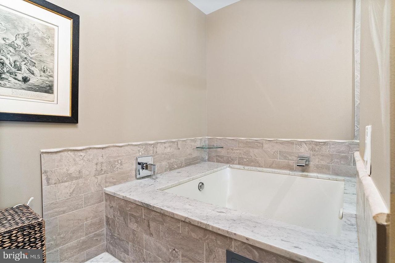 A bathroom with a large tub and a picture on the wall.