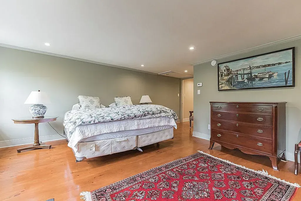 A bedroom with a large bed , dresser and rug.