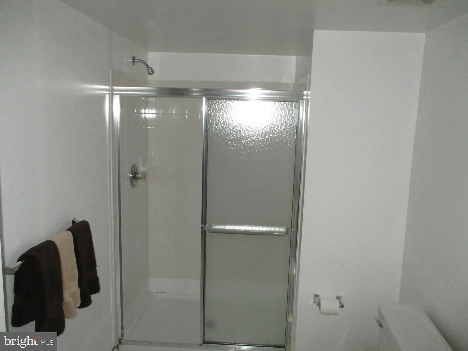 A bathroom with a sliding glass shower door and a toilet.