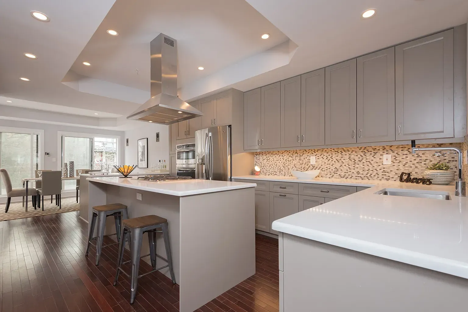 A kitchen with gray cabinets , white counter tops , and a large island.